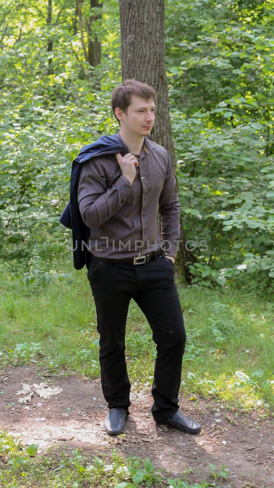 portrait of young businessman in forest, trees in the background.