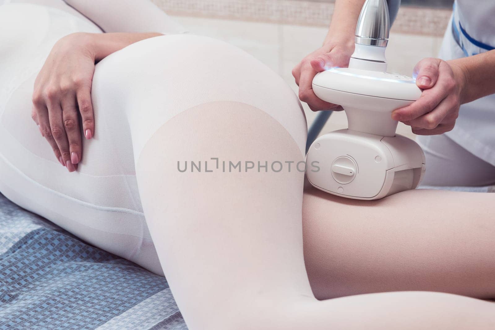 Woman in special white suit getting anti cellulite massage in a spa salon. LPG, and body contouring treatment in clinic. Lipomassage procedure on female body.