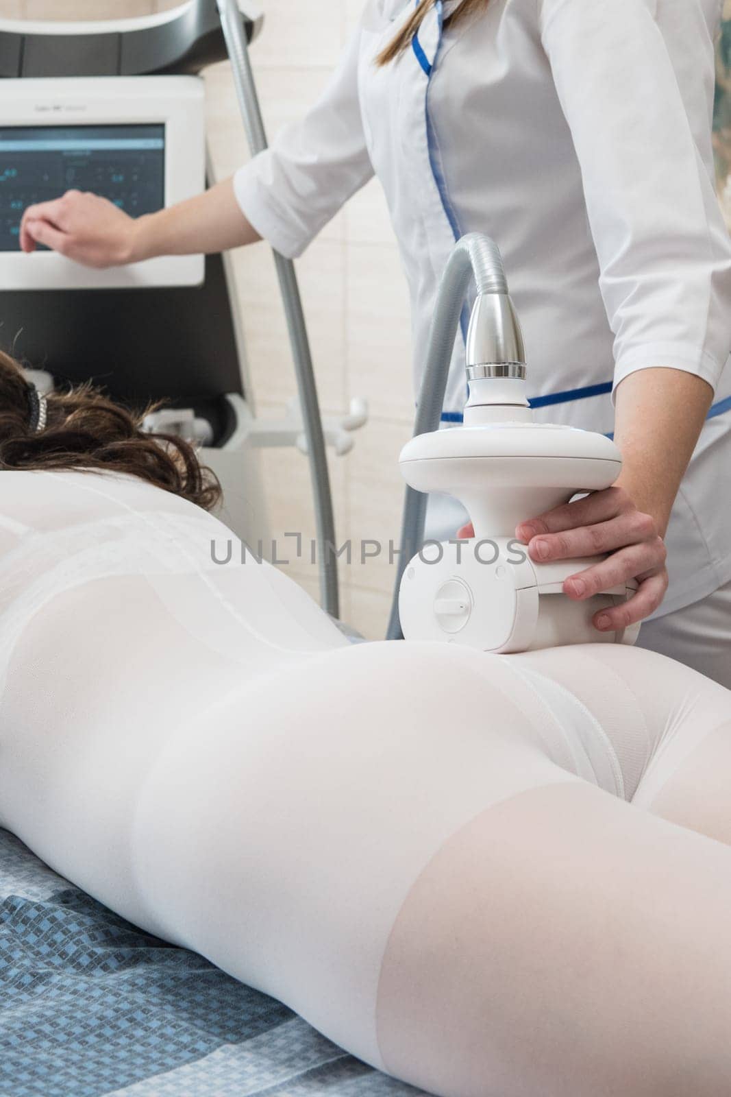 Woman in special white suit getting anti cellulite massage in a spa salon. LPG, and body contouring treatment in clinic. Lipomassage procedure on female body.