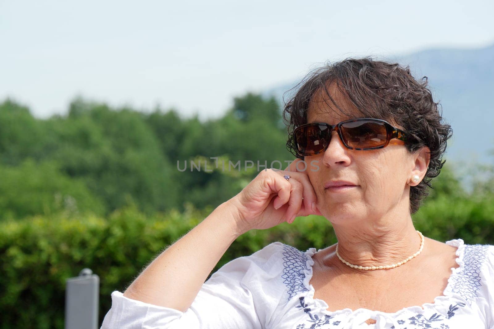 a portrait of  smiling middle age woman sitting in garden at home