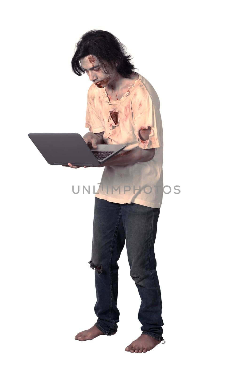 Creepy asian male zombie typing with laptop isolated over white background
