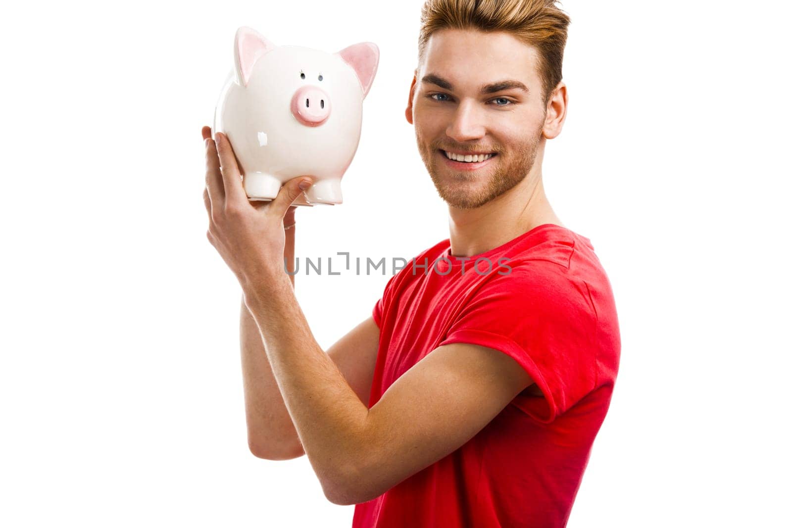 Handsome young holding a piggybank and smiling, isolated over a white background