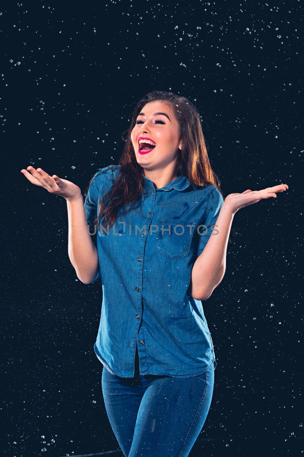 Young beautiful woman with splash of rain. Studio shot
