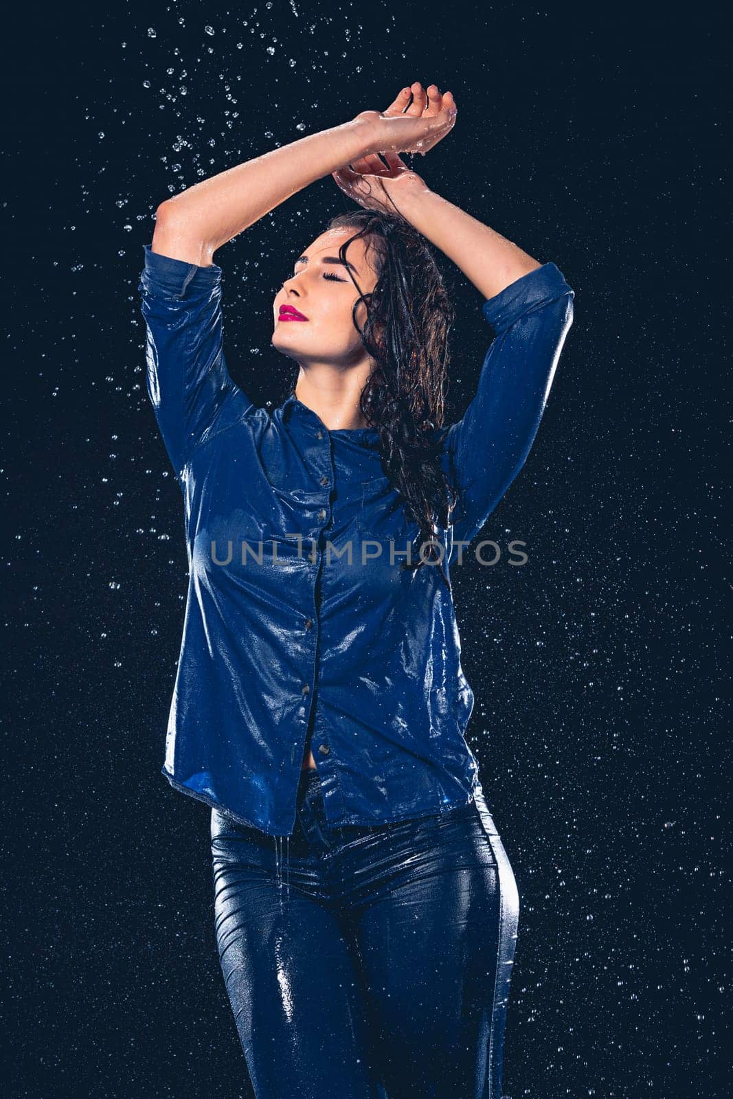 Young beautiful woman with splash of rain. Studio shot
