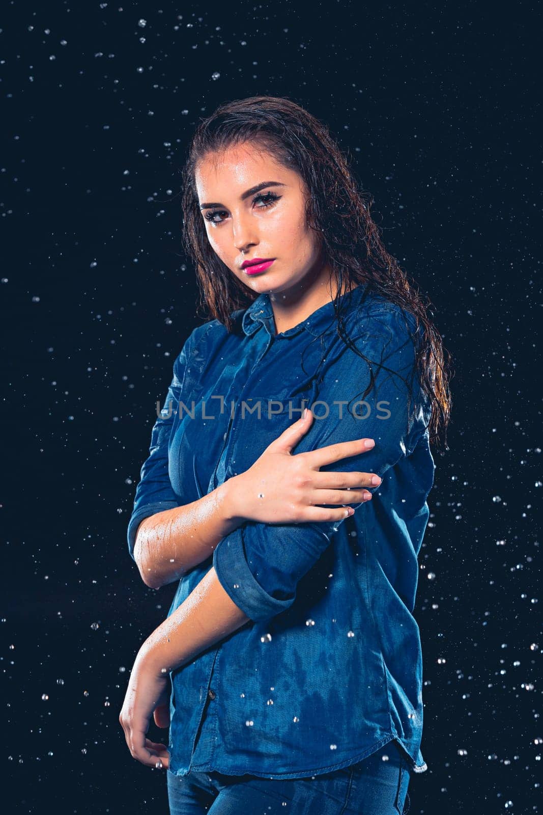 Young beautiful woman with splash of rain. Studio shot