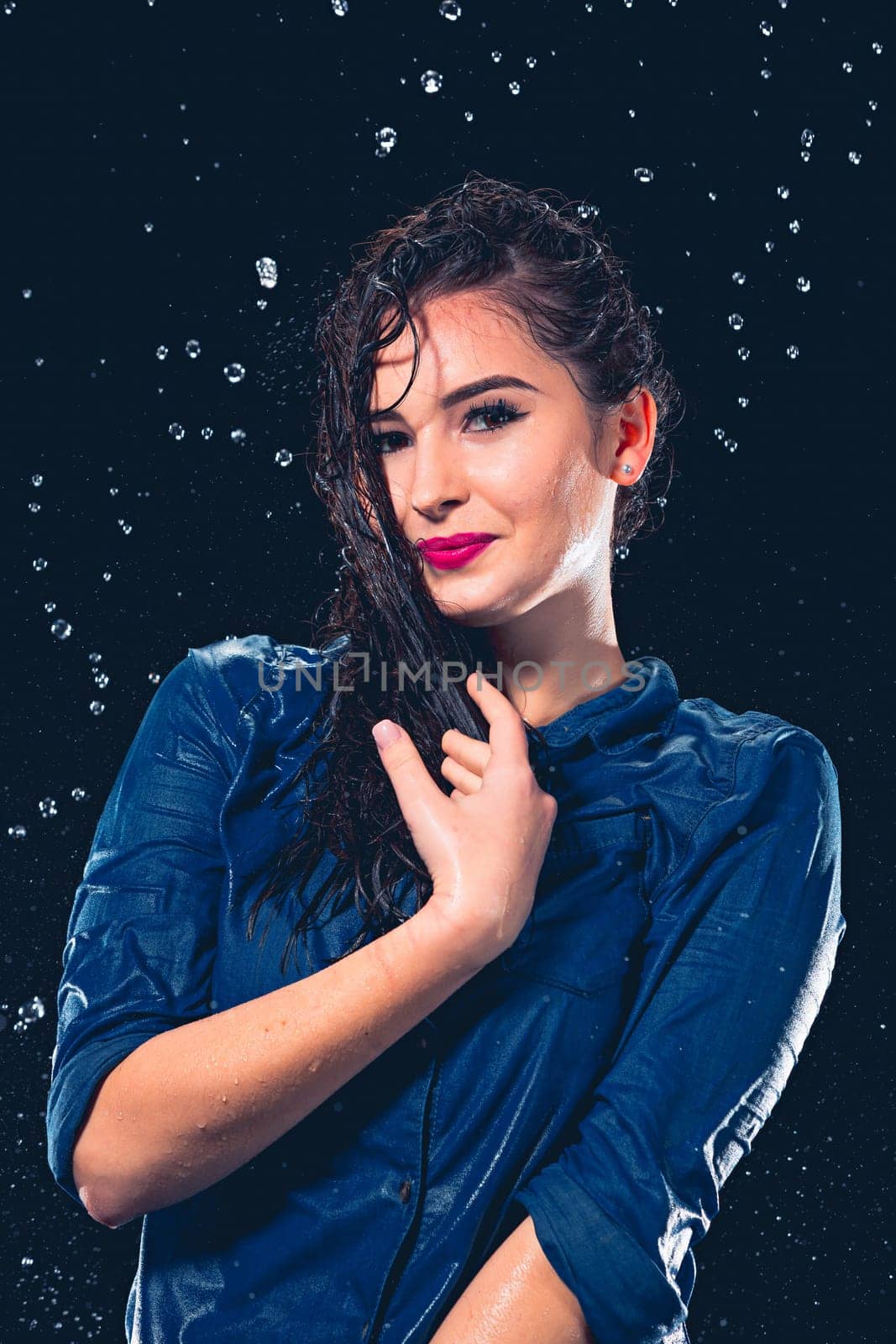 Young beautiful woman with splash of rain. Studio shot