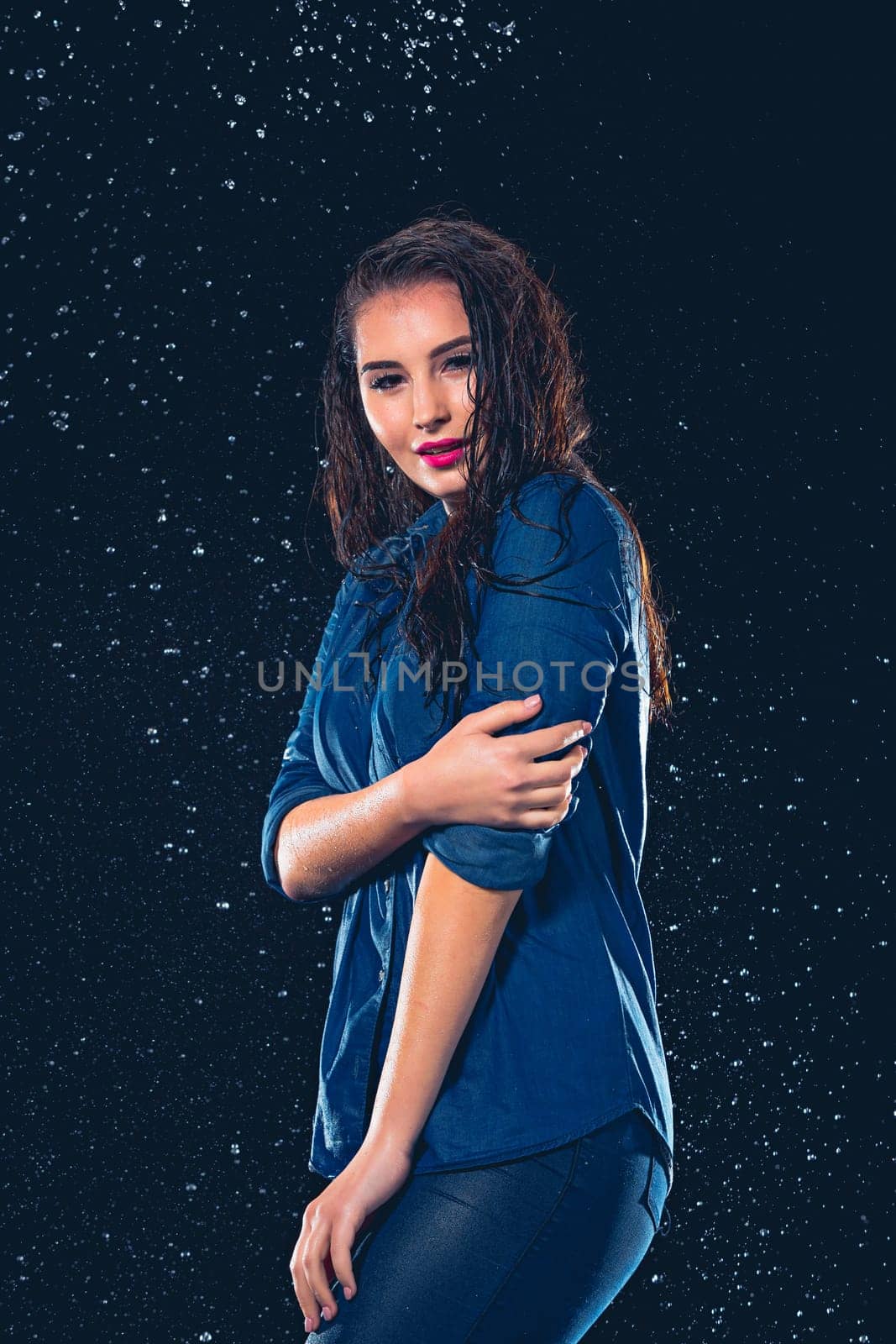 Young beautiful woman with splash of rain. Studio shot