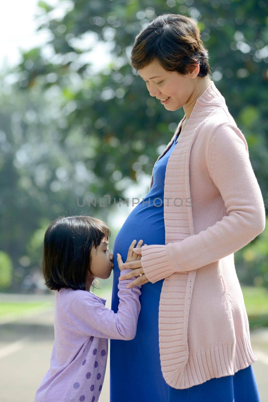 Pregnant mother and her daughter posing on the outdoor when summer