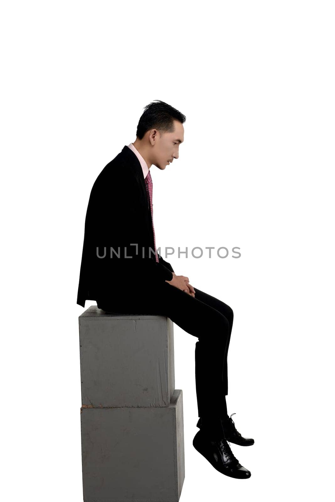 Asian business man feeling sad sitting on the box isolated over white
