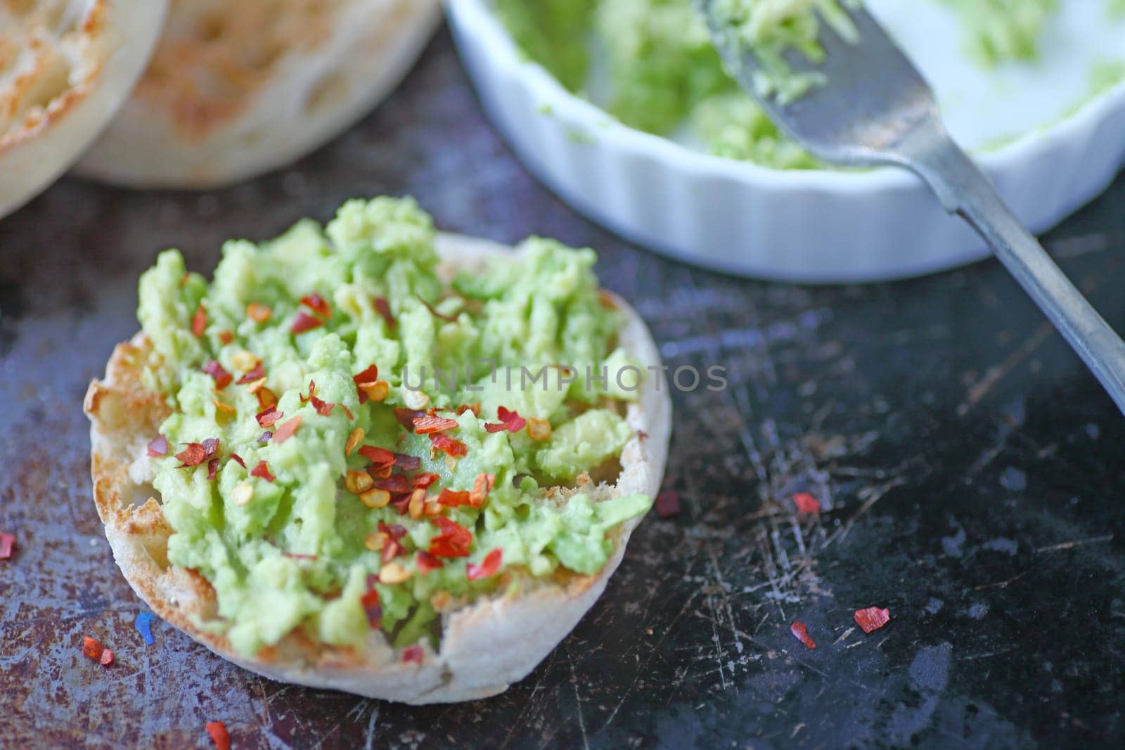 Toasted English muffins with mashed avocado and red pepper flakes