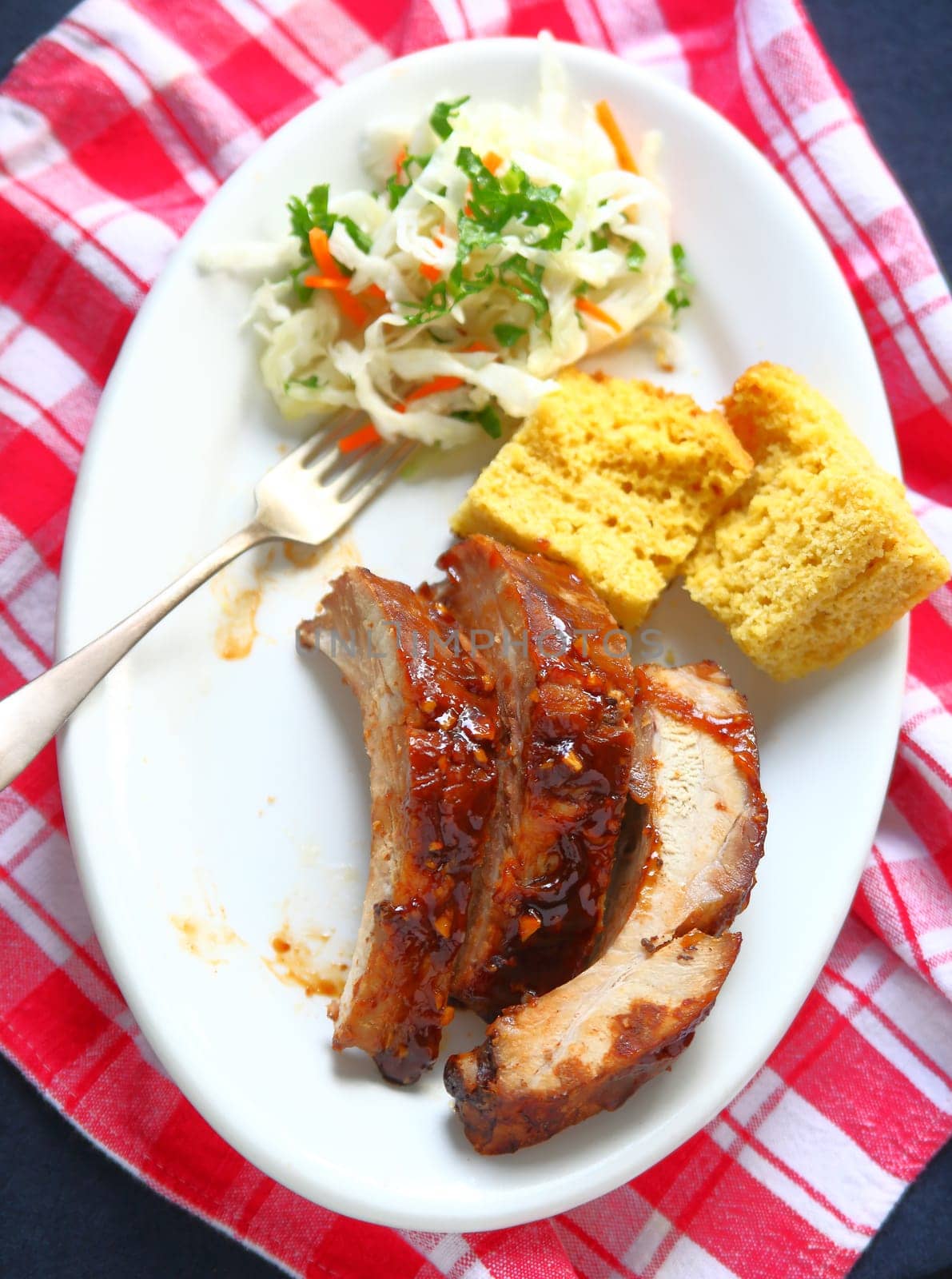 Overhead view of garlic-barbecue sauce-glazed pork baby back ribs with cornbread and coleslaw