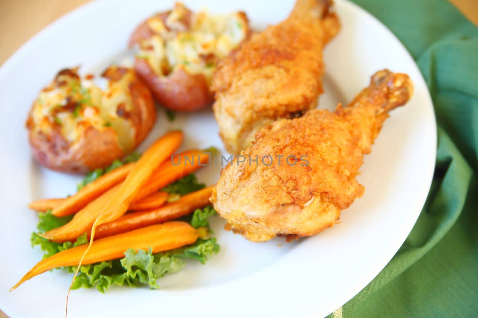 Two fried chicken legs with smashed potatoes and carrots