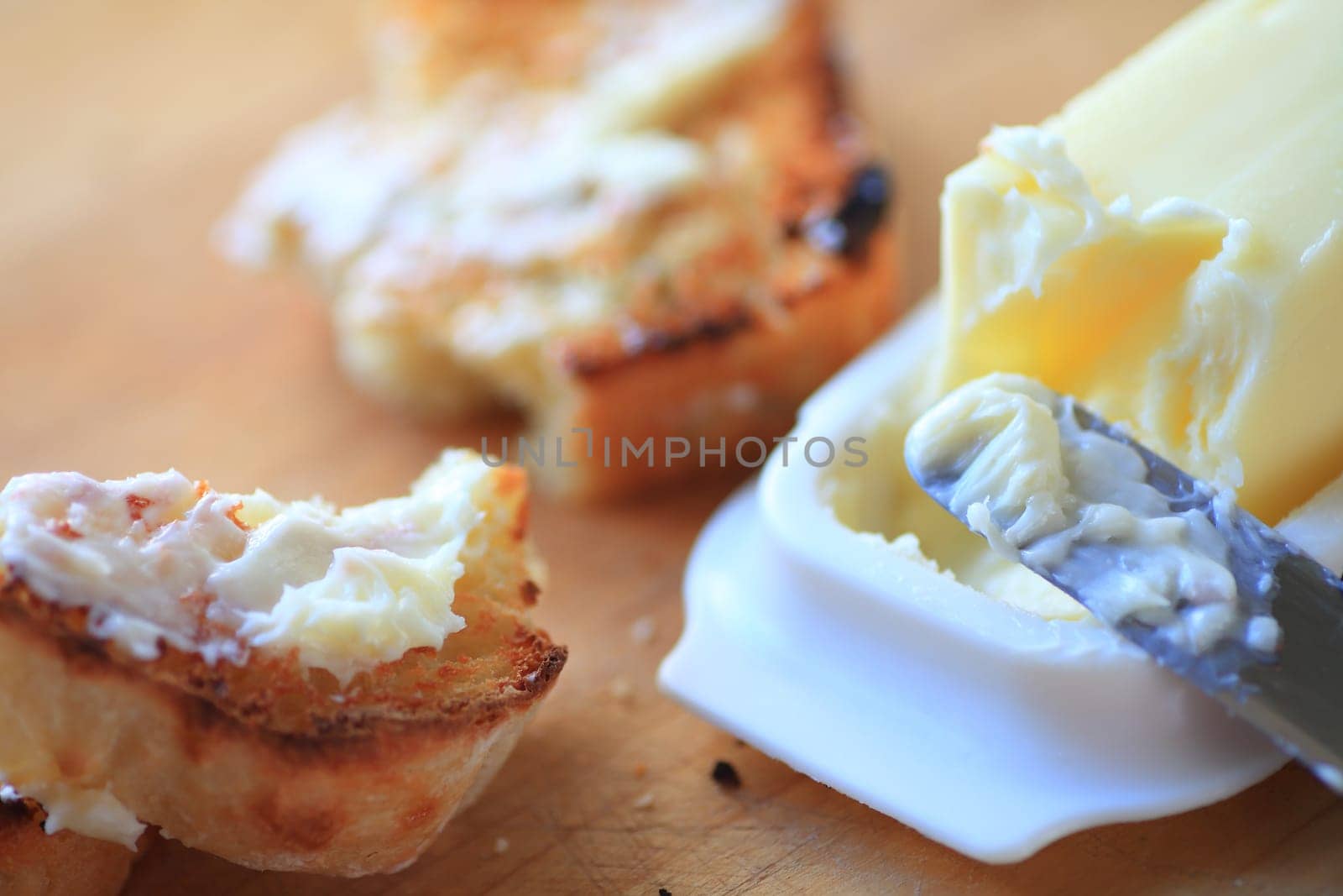 Broken slice of buttered toast with knife and butter dish