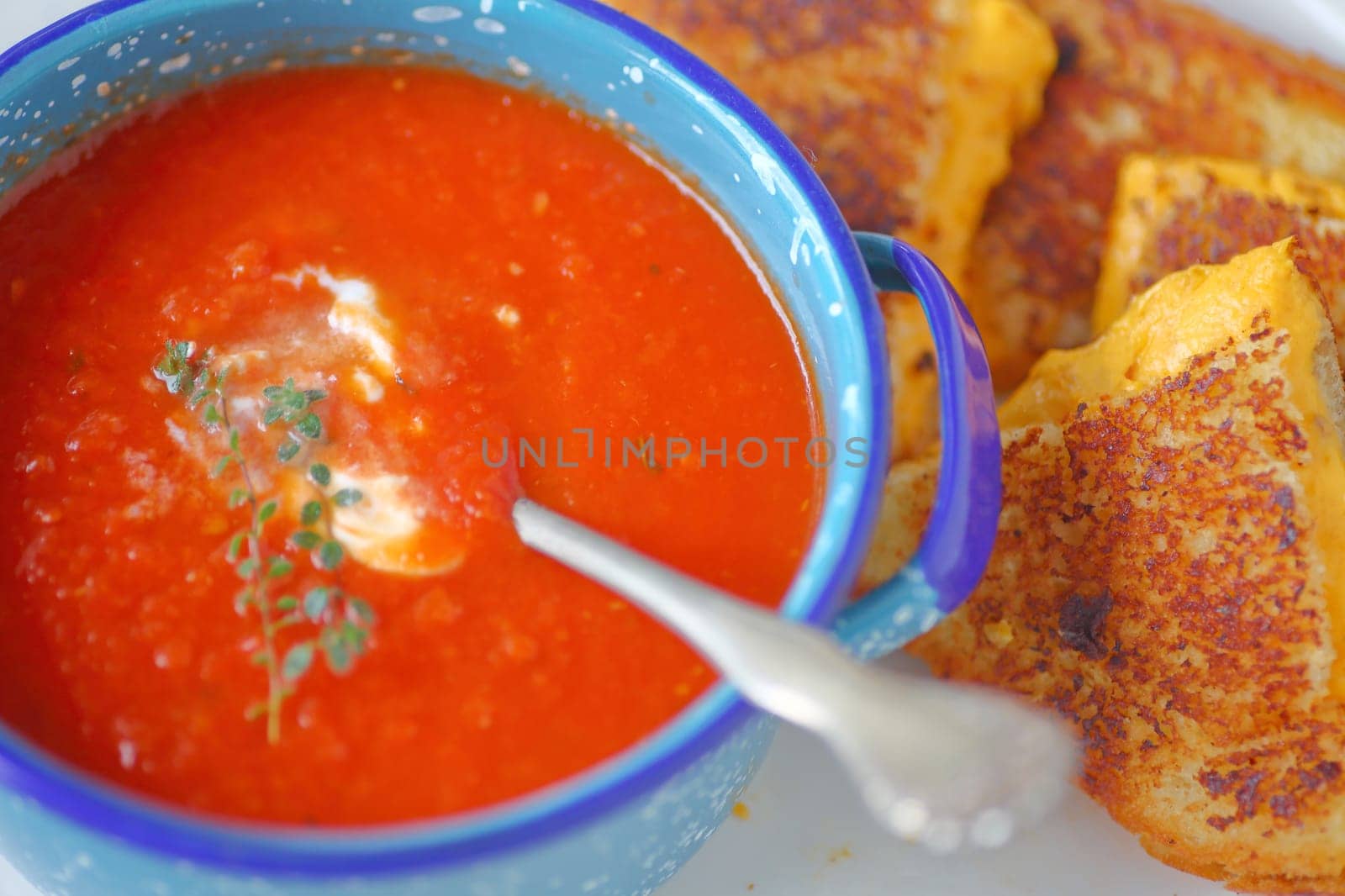 Tomato soup in an enamelware bowl with a grilled cheese sandwich cut in triangles