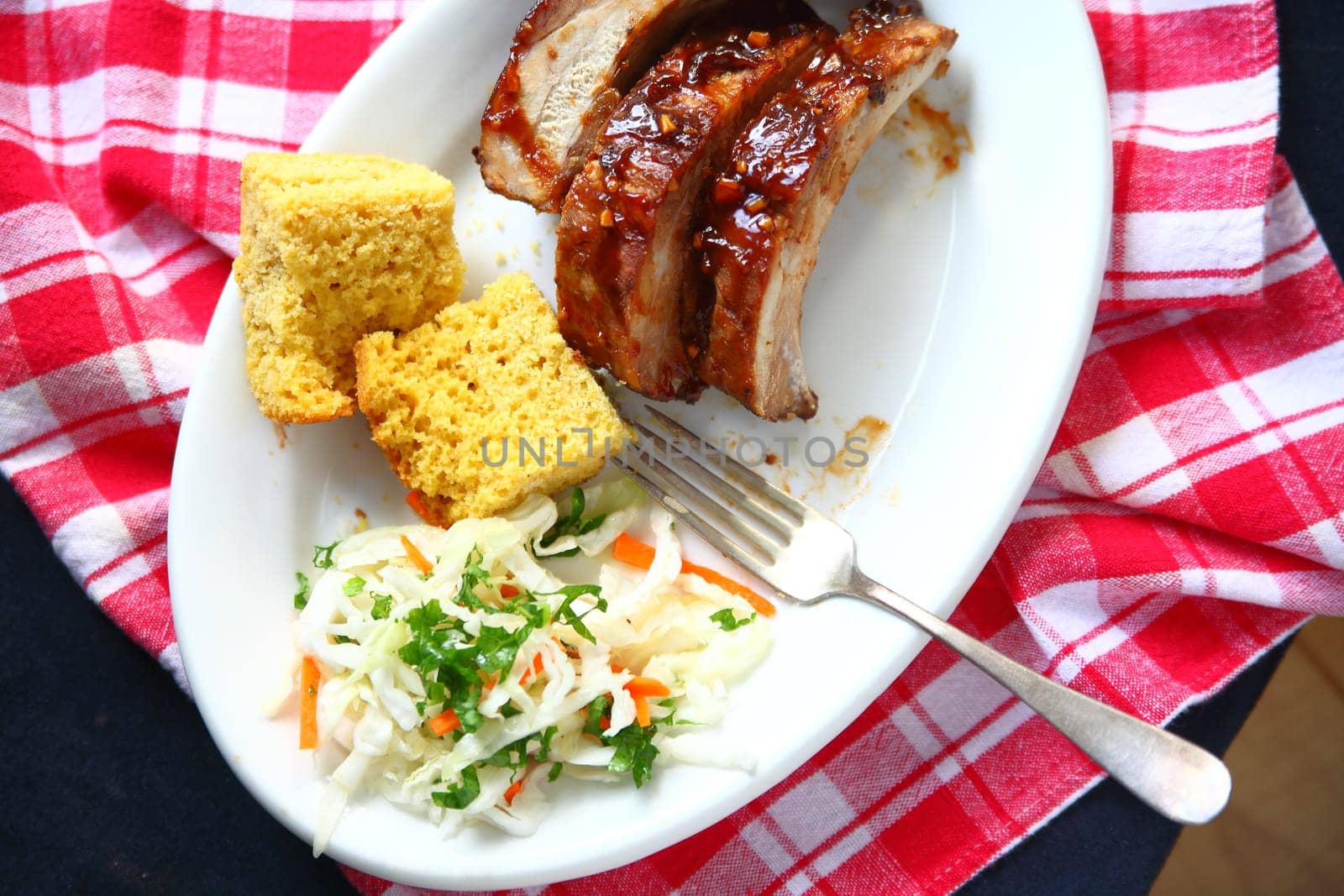 Meal of baby back ribs with garlic barbecue sauce, cornbread and coleslaw