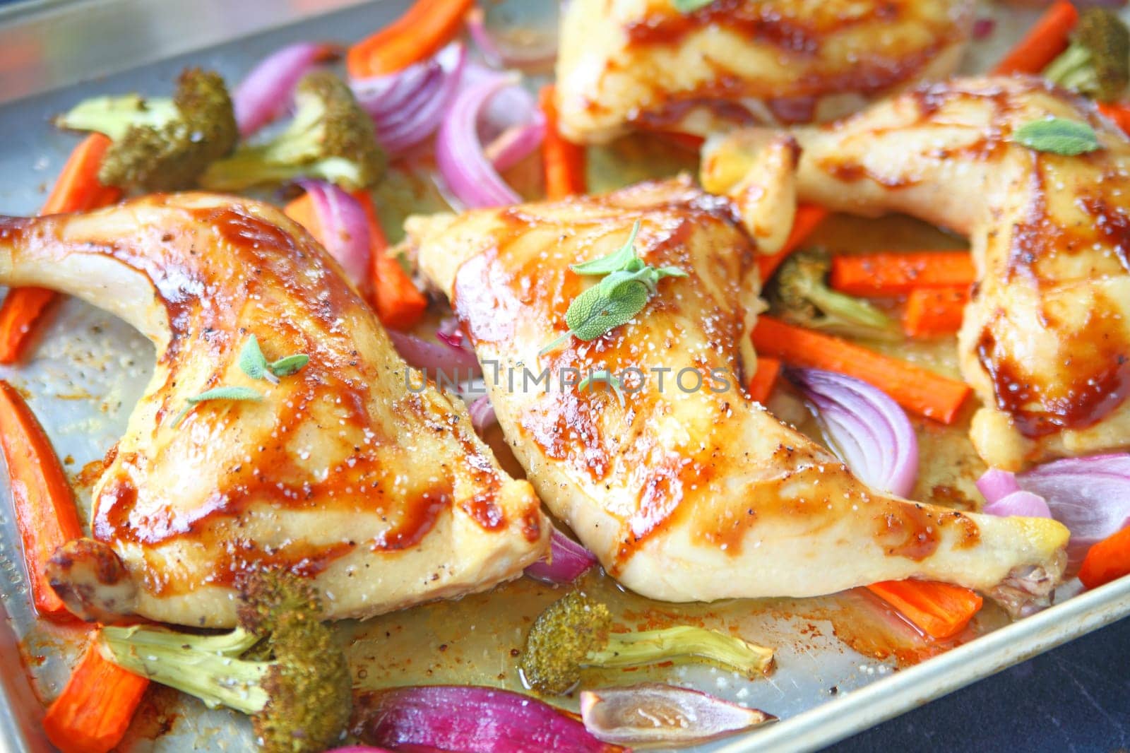 Chicken quarters roasted with carrots, onions and broccoli on sheet pan