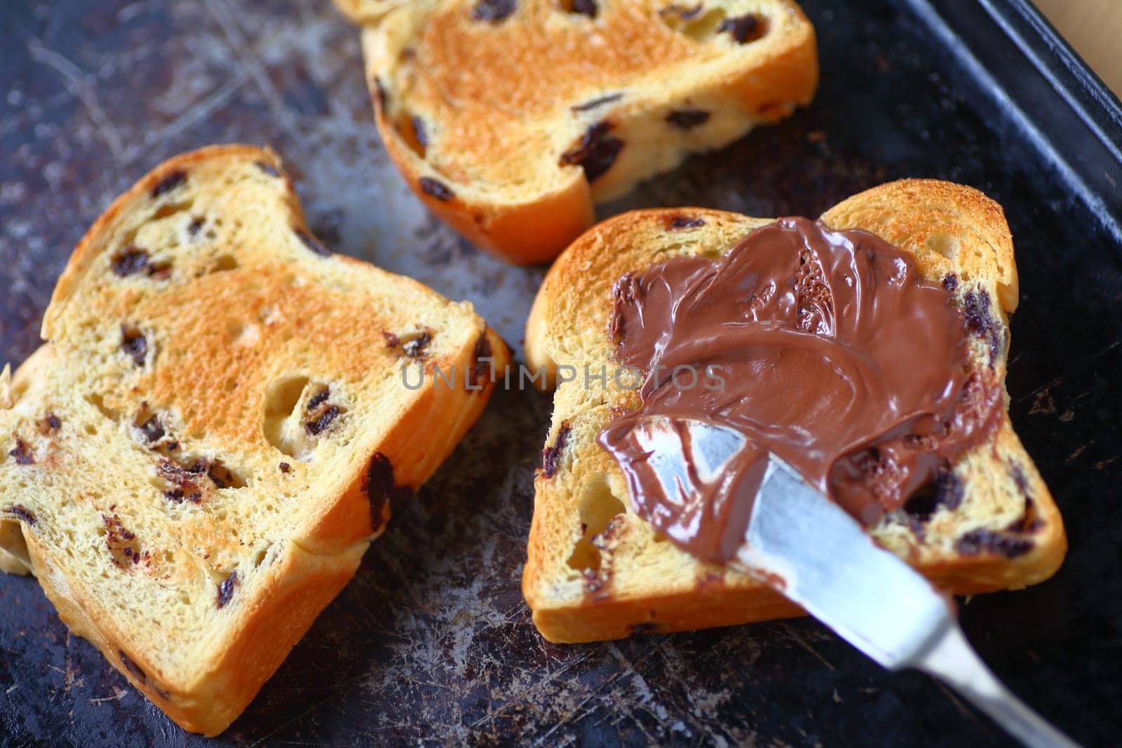 Chocolate chip brioche slices, one with chocolate hazelnut spread on an old cookie sheet pan