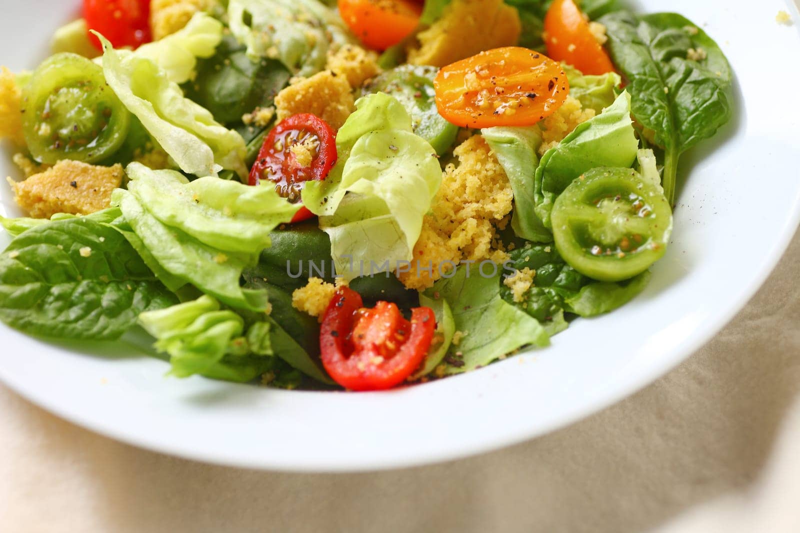 Closeup of butter lettuce and spinach salad with crumbled cornbread