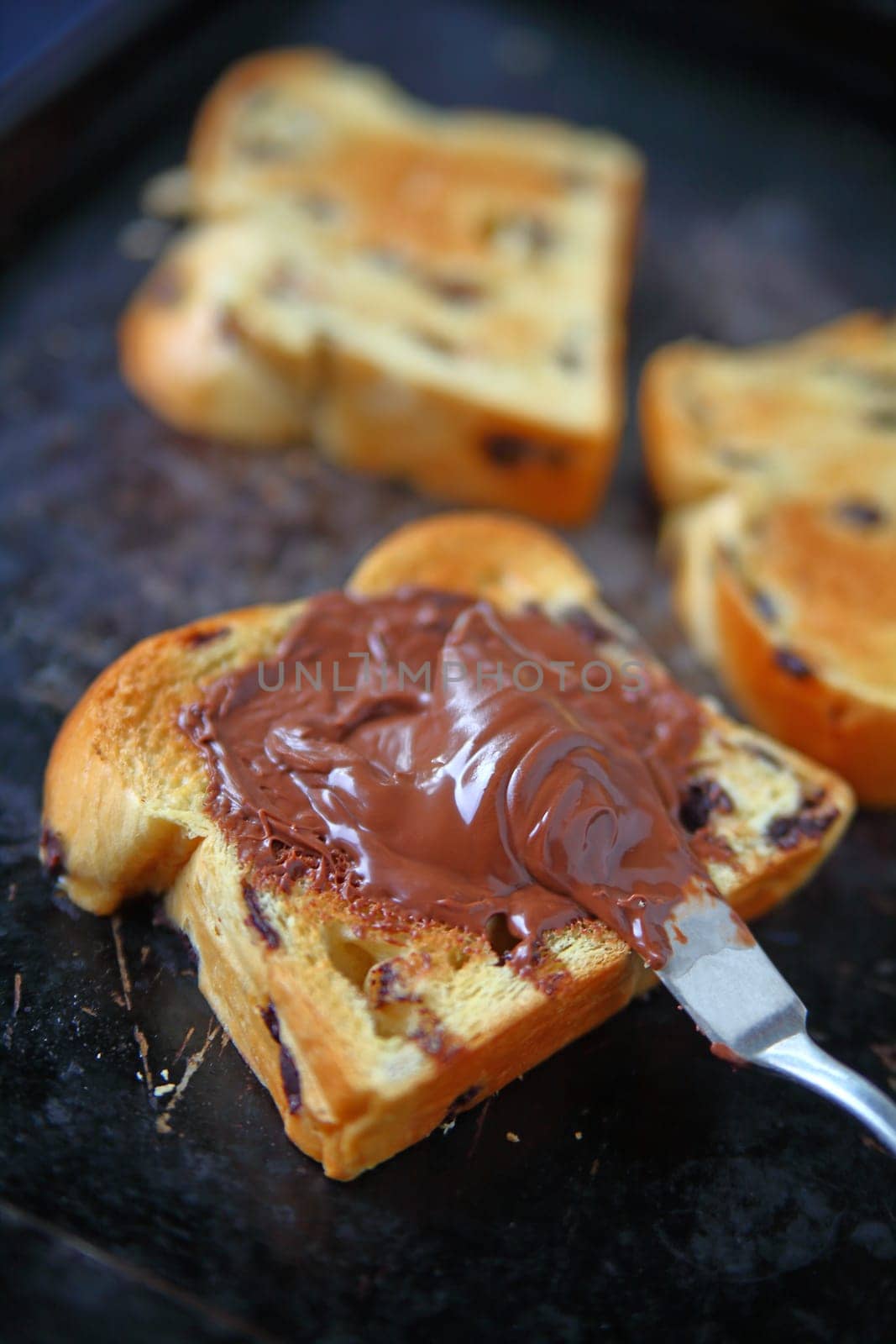 Slices of chocolate chip brioche, one with chocolate hazelnut spread, on an old metal cookie sheet