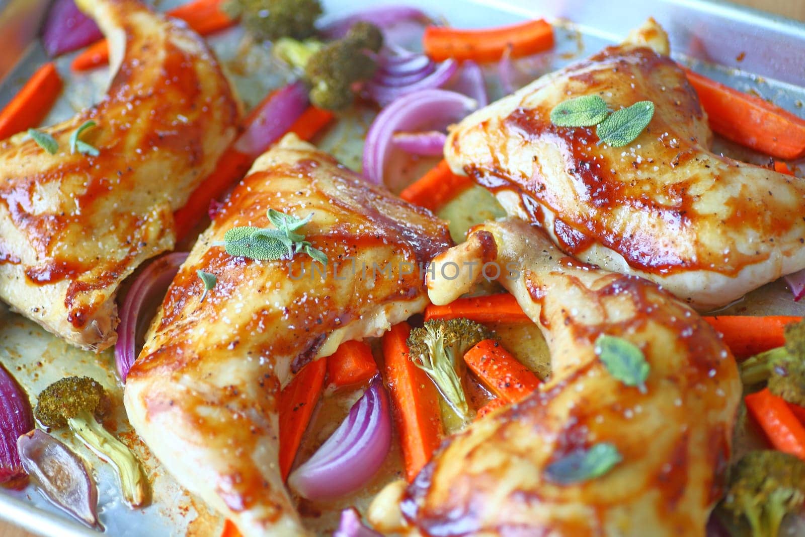 Chicken quarters with fresh sage and coarse salt and hoisin glaze with assorted vegetables in roasting pan