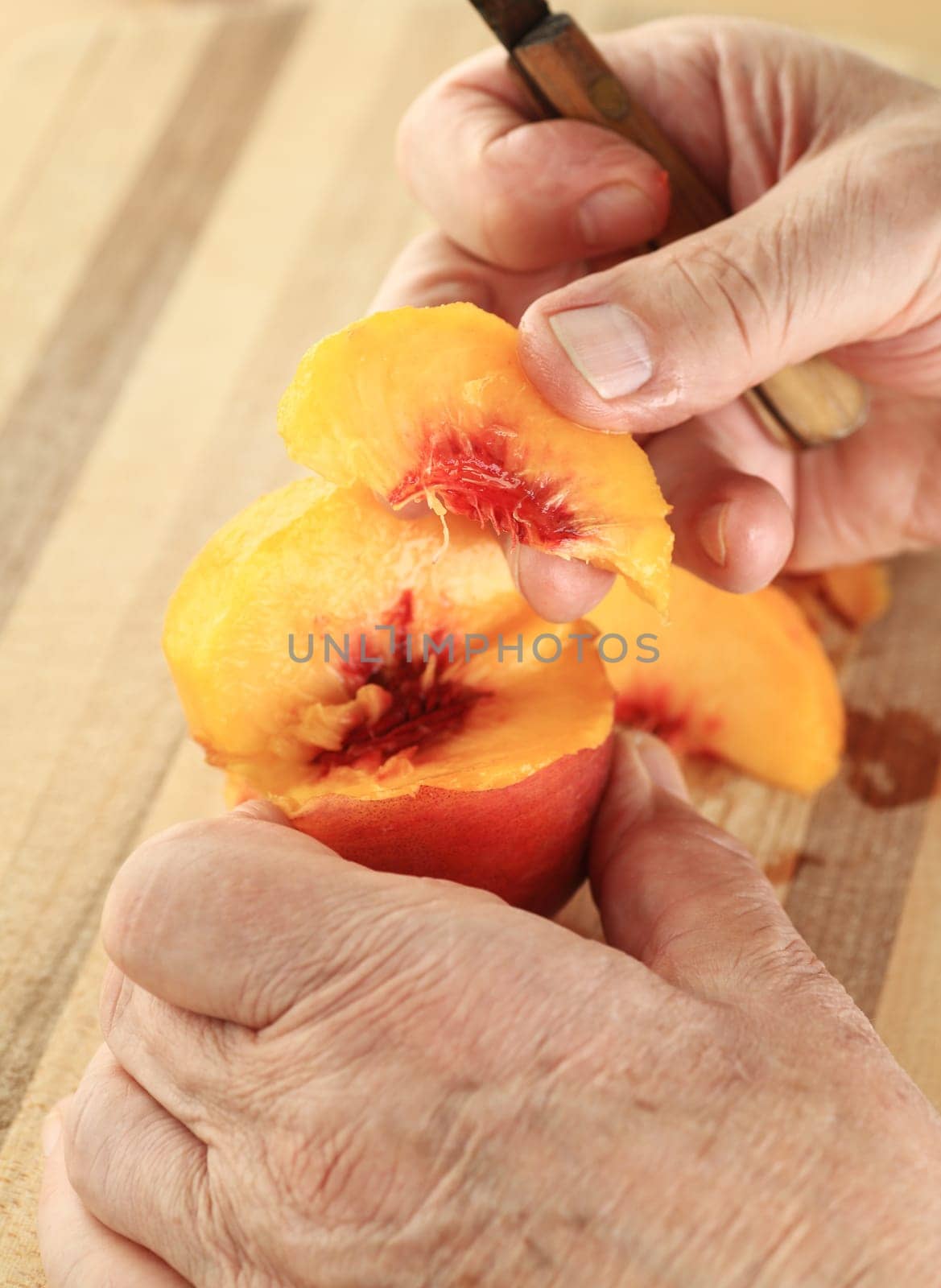A man has cut a slice from a fresh, juicy peach.