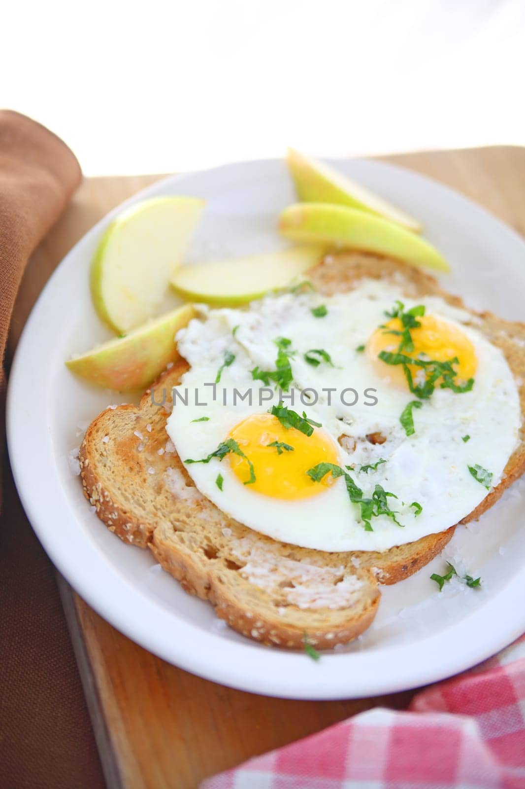 Two fried eggs on buttered toast with coarse salt and apple slices