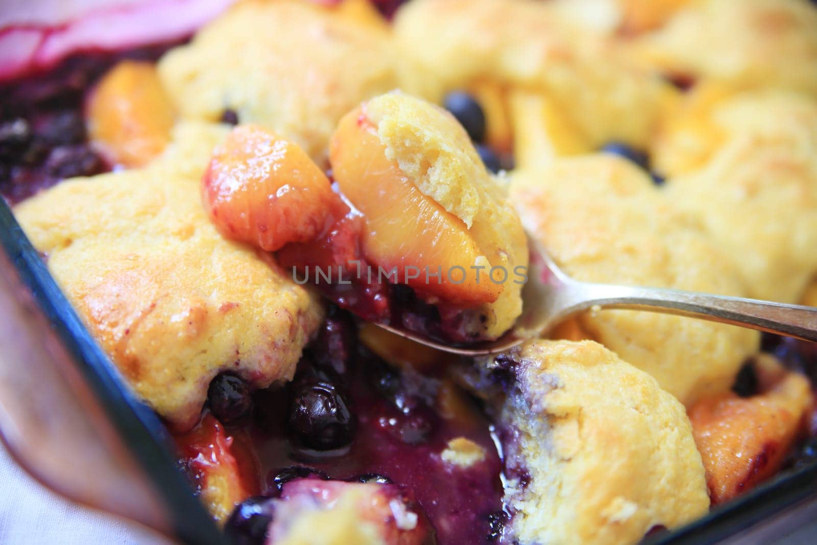 A serving spoon of fresh fruit cobbler with cinnamon