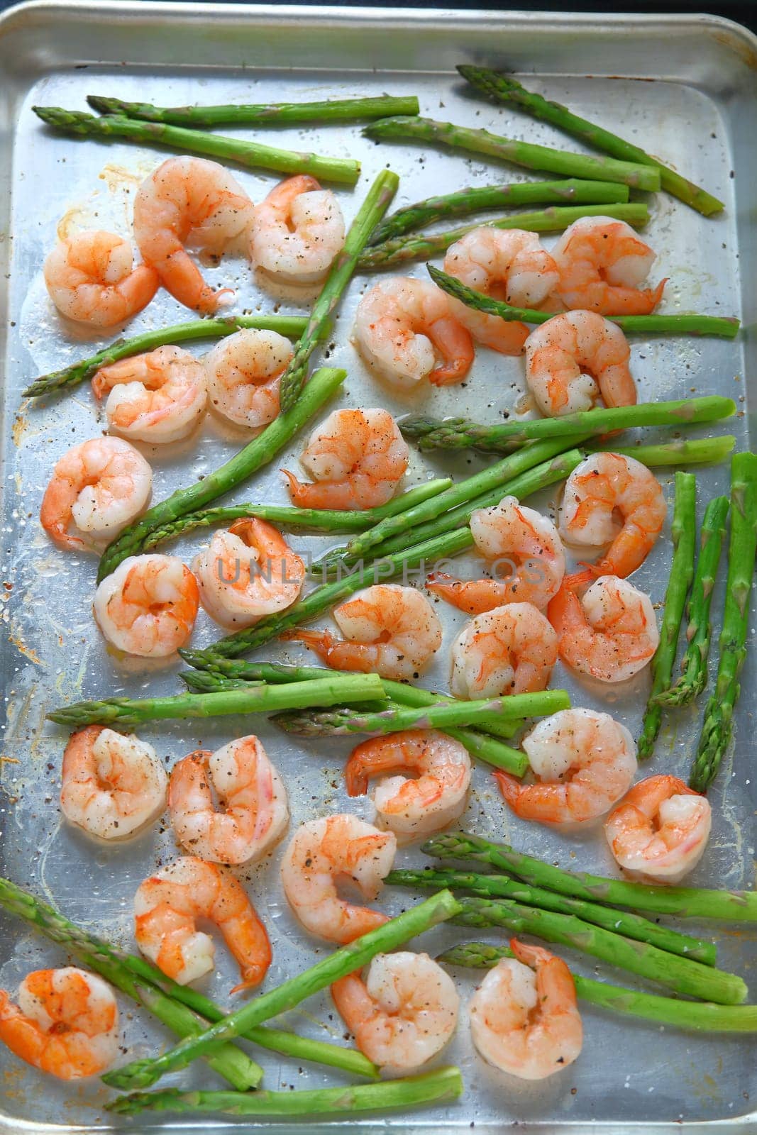 Large shrimp on a sheet pan with asparagus, black pepper and coarse salt