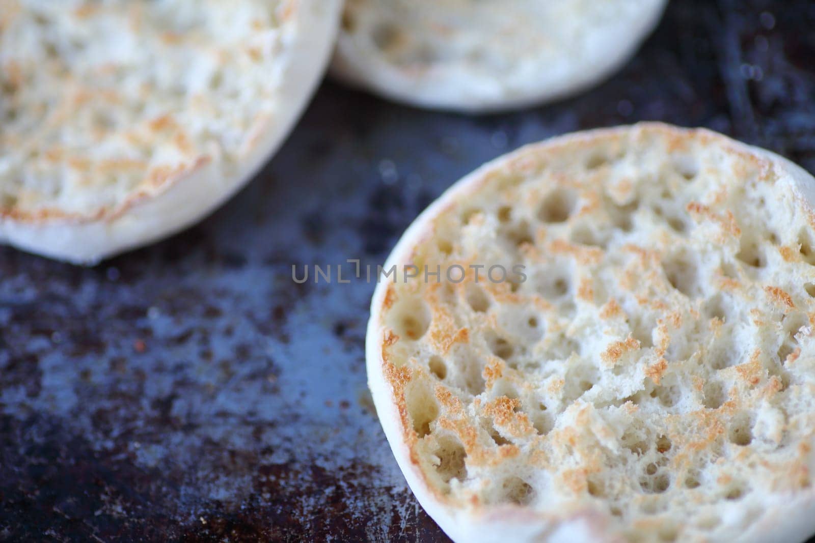 English muffin halves closeup, toasted, on a worn baking pan