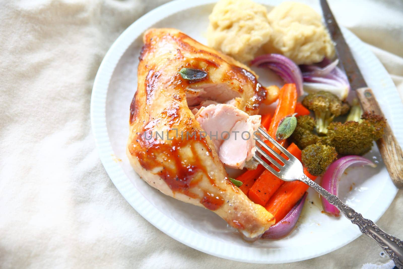 Plate of chicken with carrots and onions on a tablecloth with room for text
