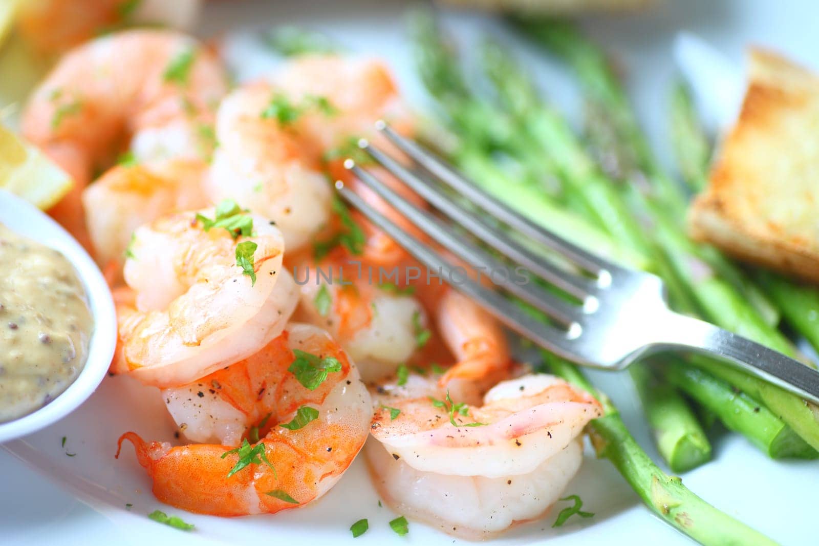 Closeup of shrimp dinner with asparagus, garlic bread and a grainy mustard and mayo sauce