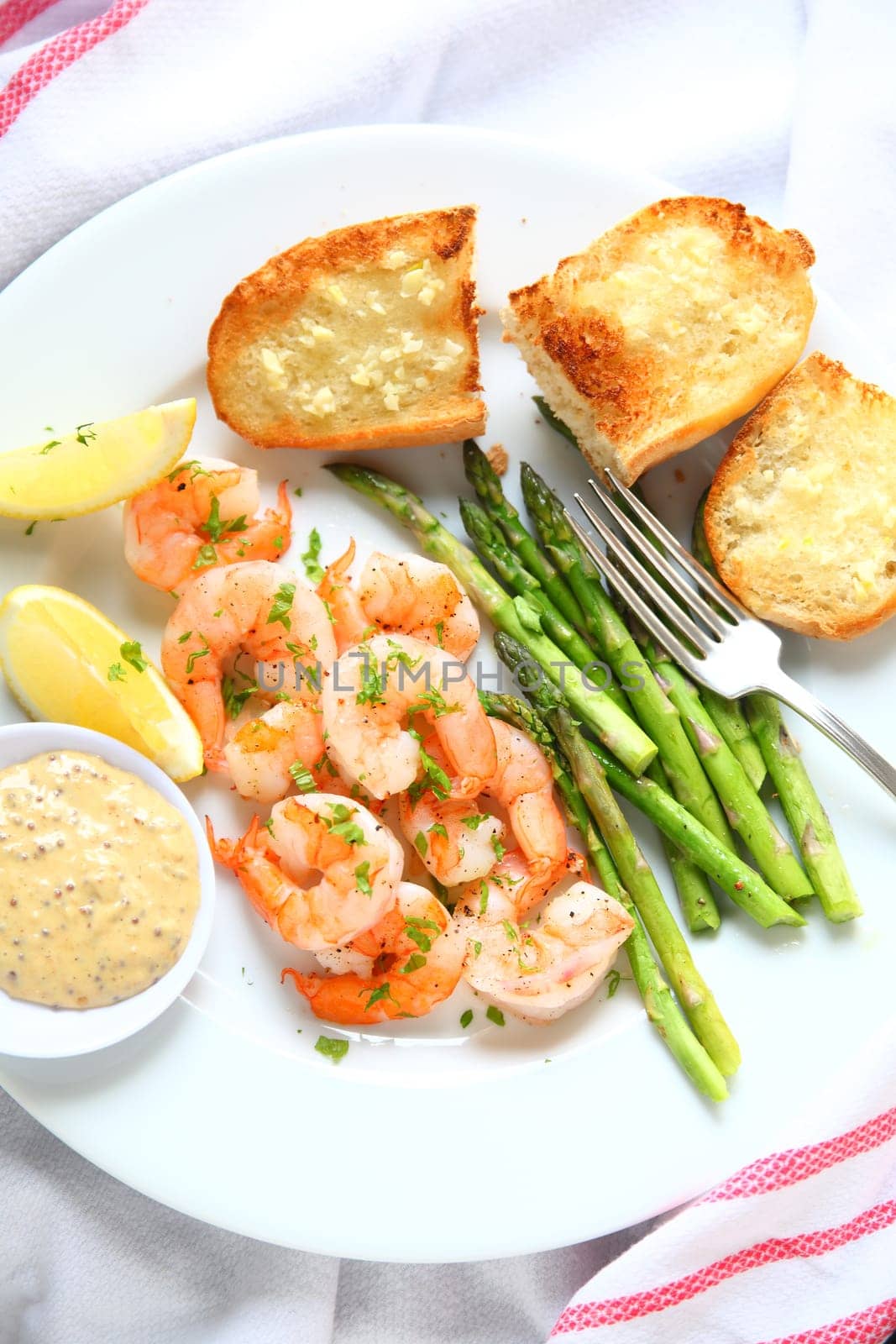 Shrimp dinner with asparagus, garlic bread, grainy-mustard sauce and lemon