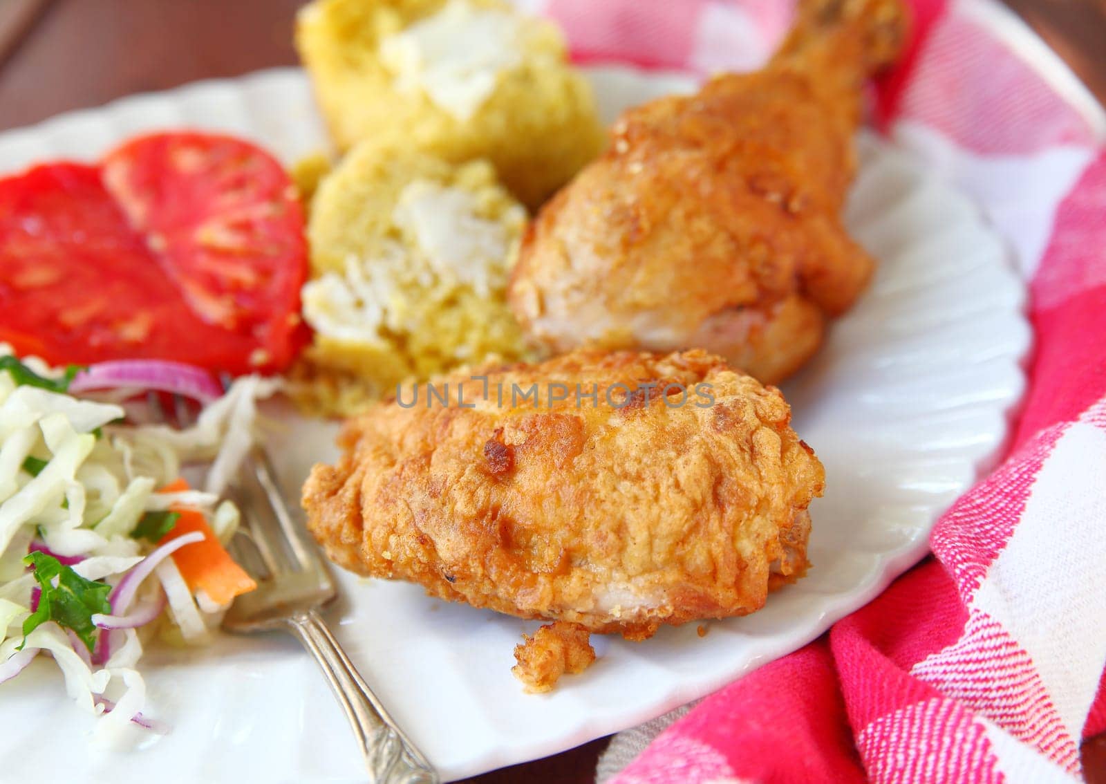 Chicken thigh and leg fried Southern-style with cornbread and vegetables