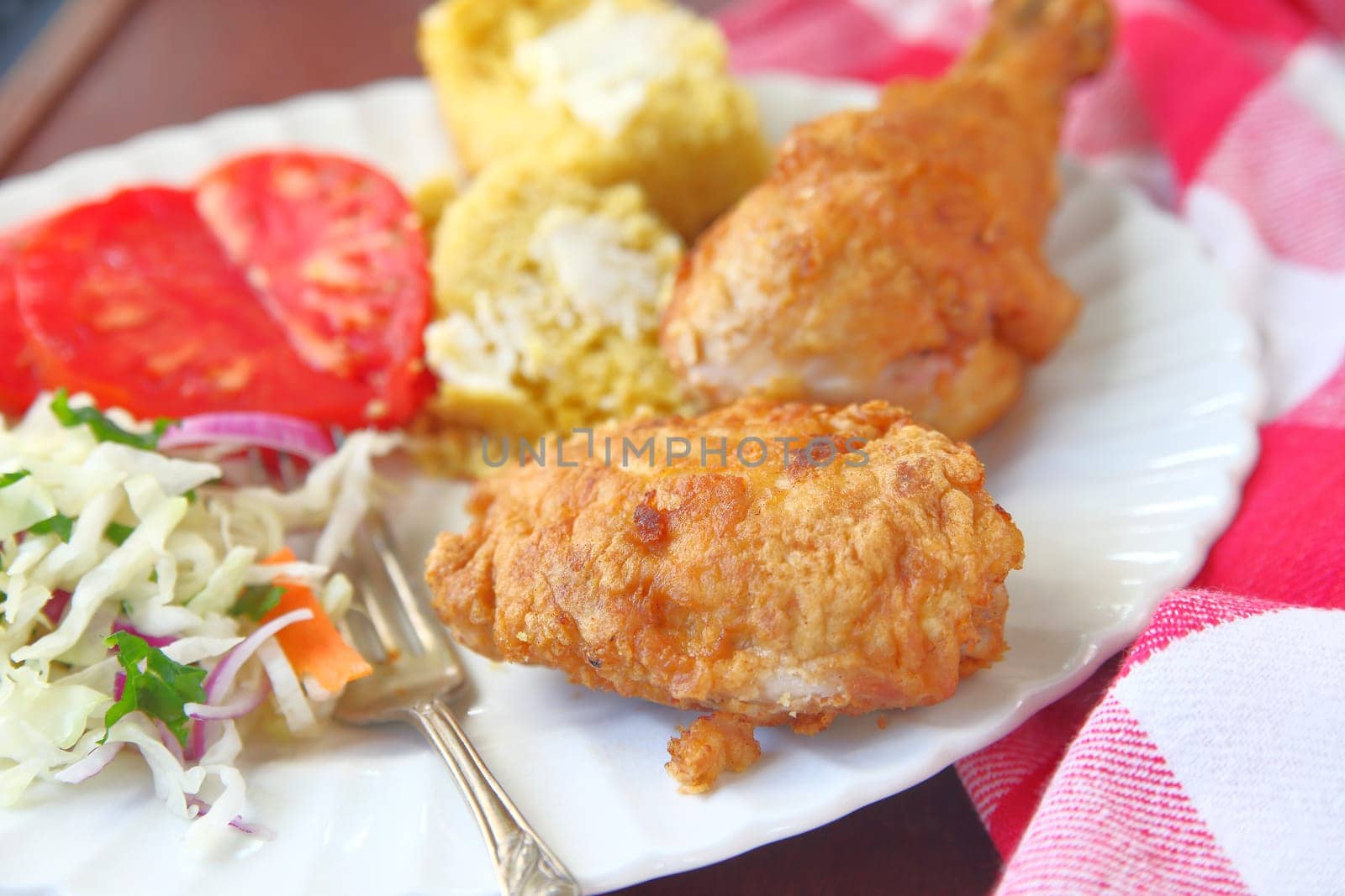 Platter of fried chicken with tomatoes, cornbread and coleslaw