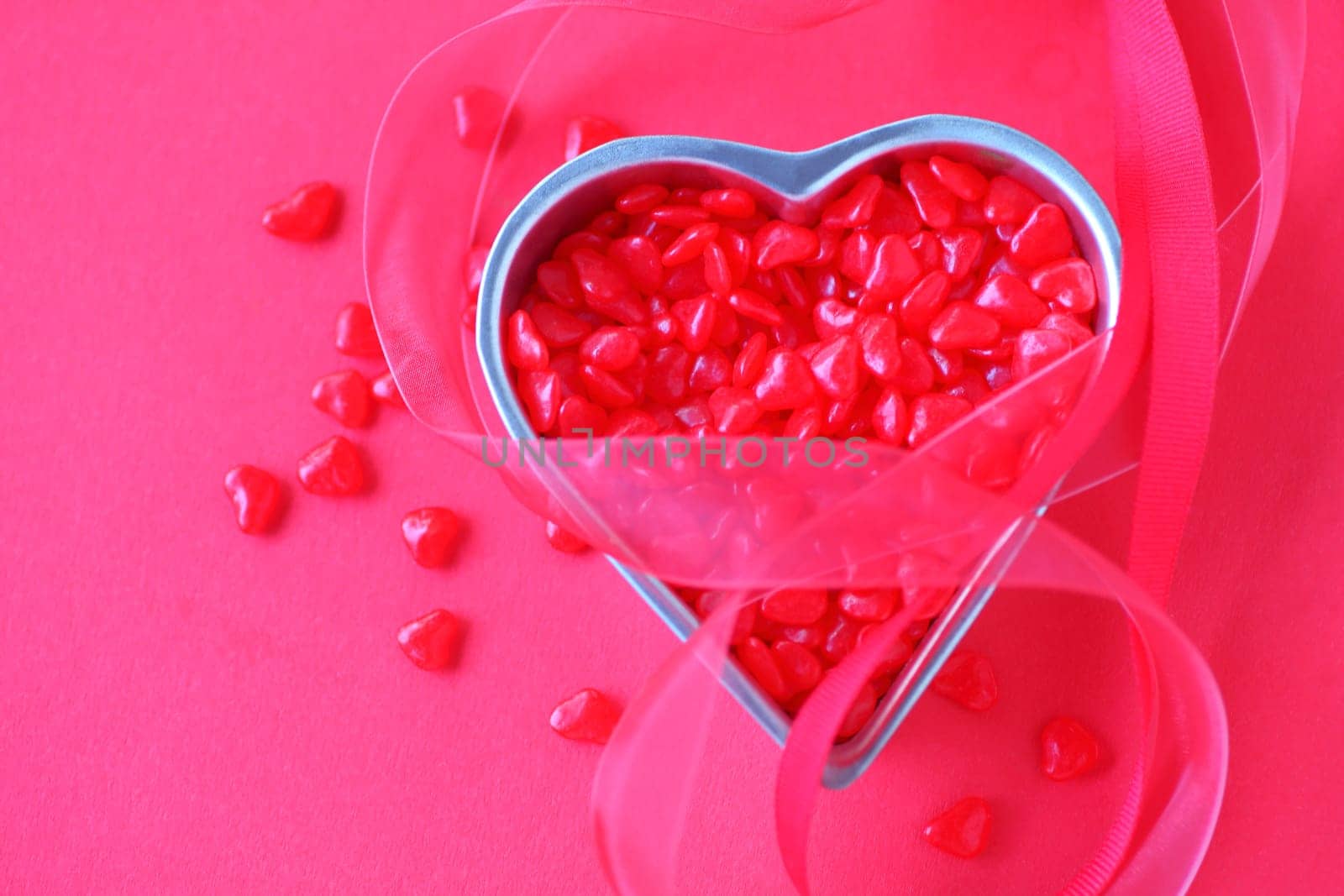 Small heart container filled with tiny red candies with red ribbons and room for text