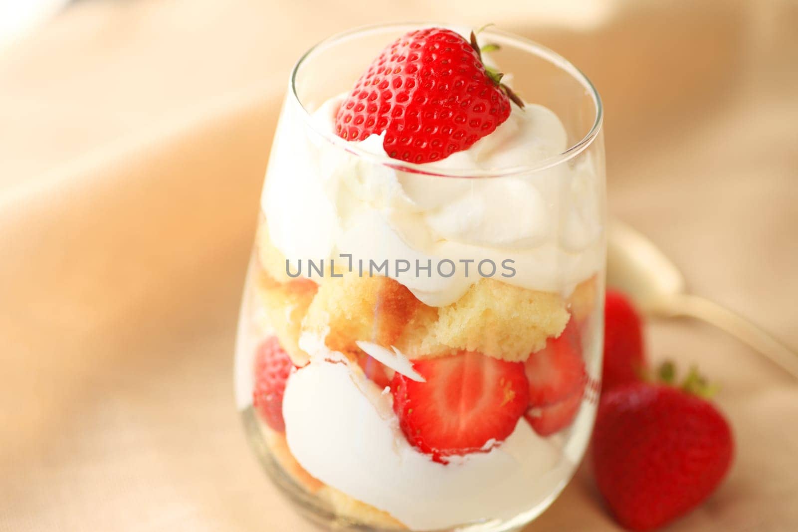 Miniature strawberry trifle in a drinking glass with whipped cream and pound cake cubes