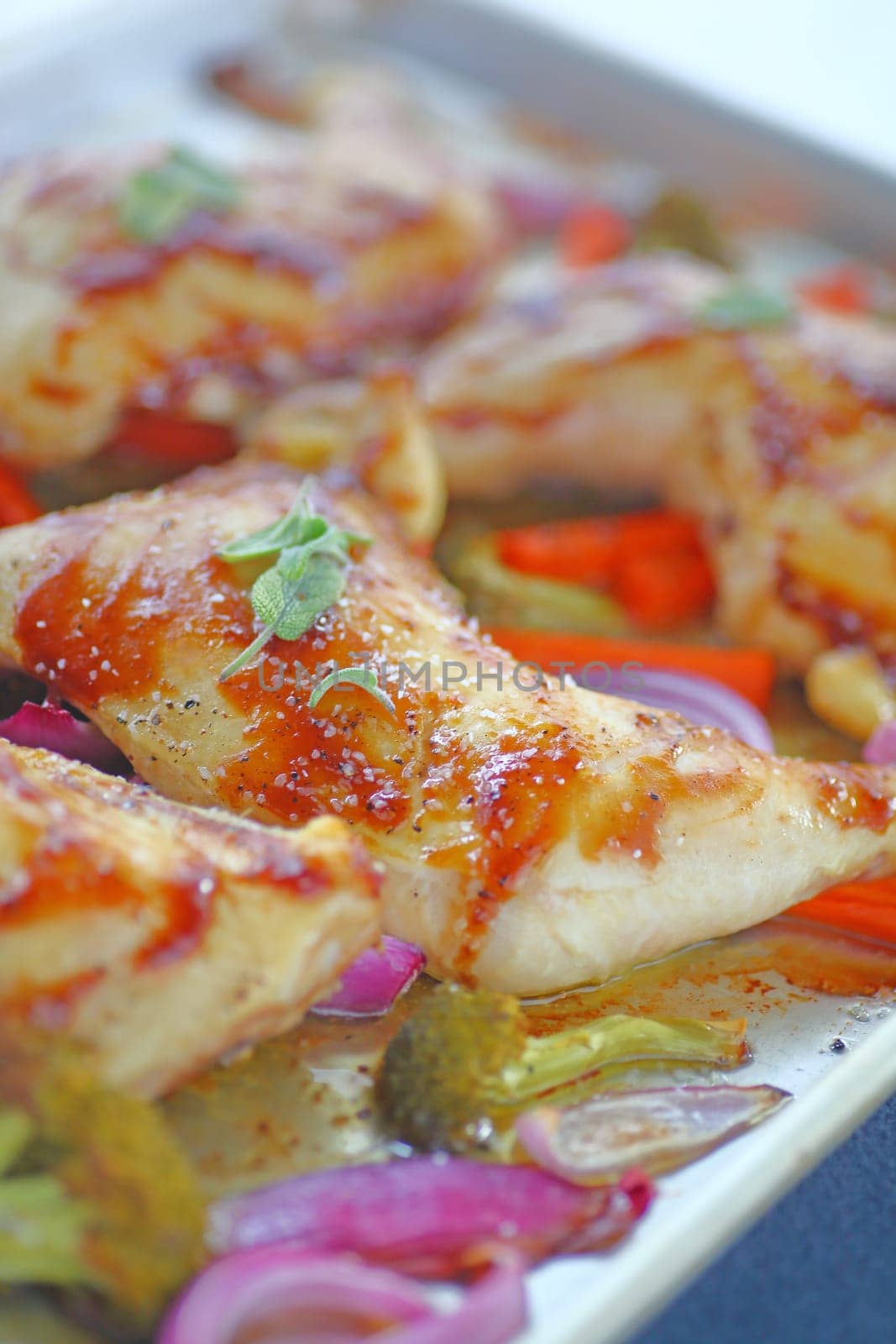 Shallow pan with roast chicken pieces, carrots, onions and broccoli