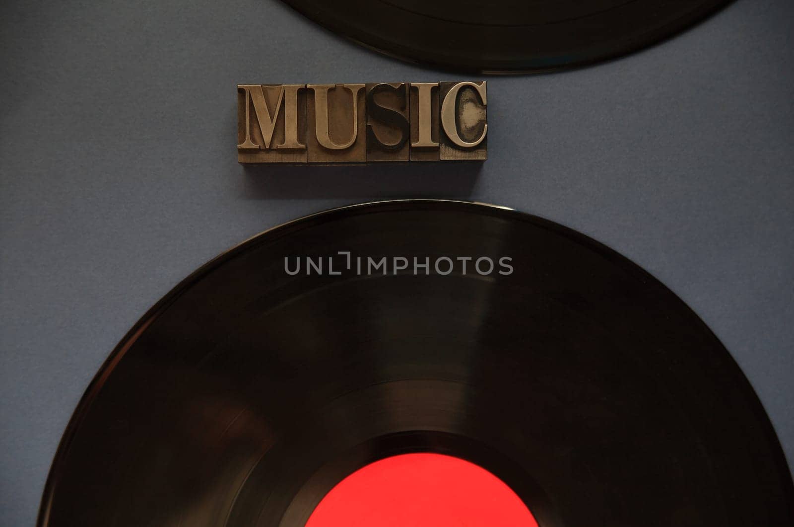 The word music in old metal type with two vinyl recordings on a dark background