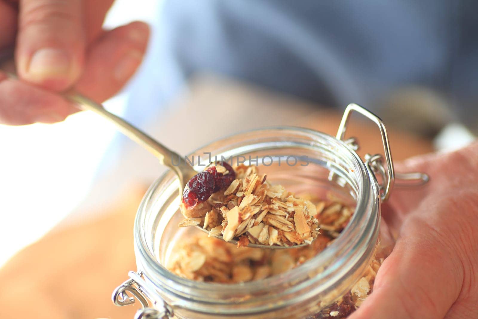 A man removes granola from a jar with a spoon
