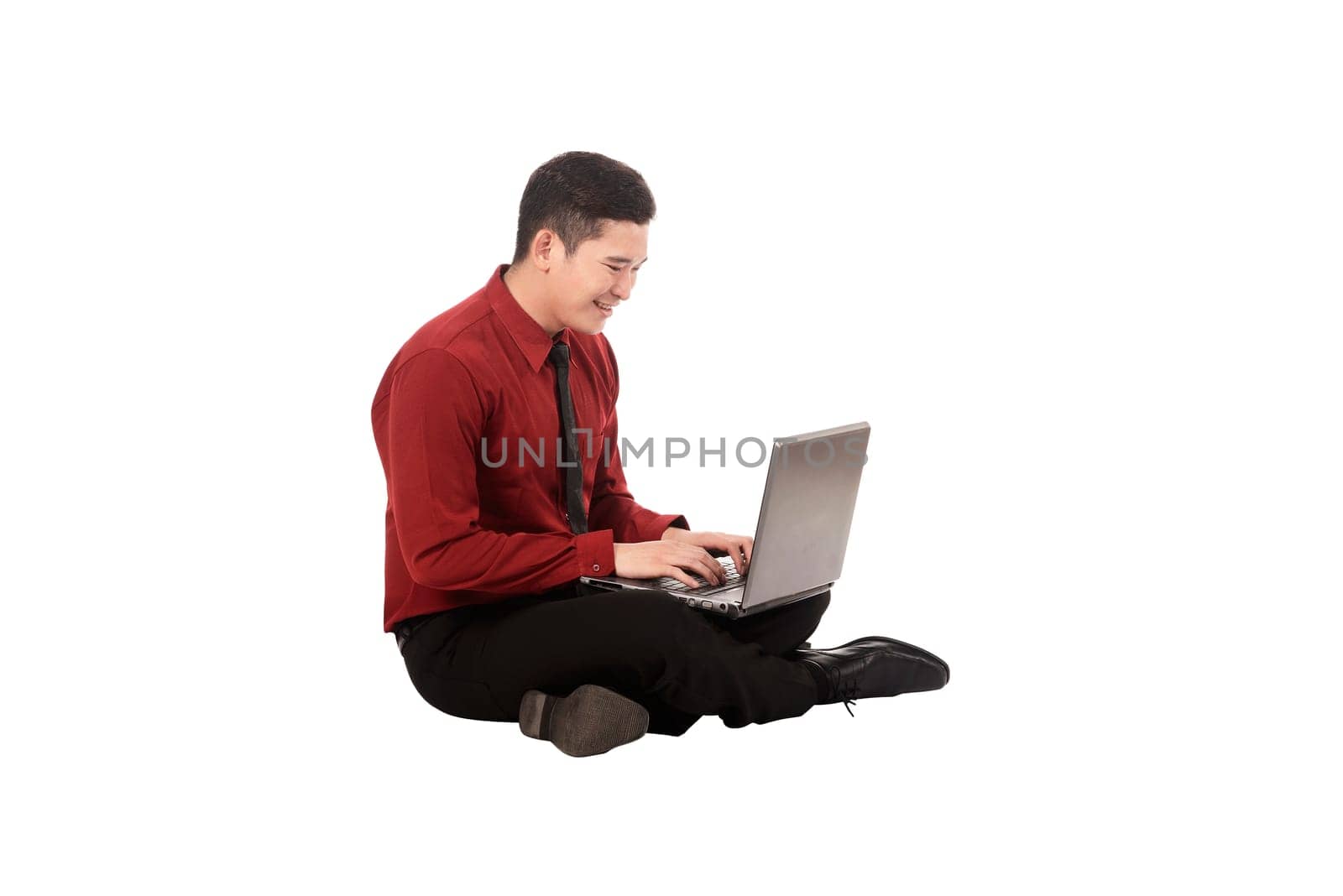 Asian business man working on a laptop and sitting on the floor isolated over white background