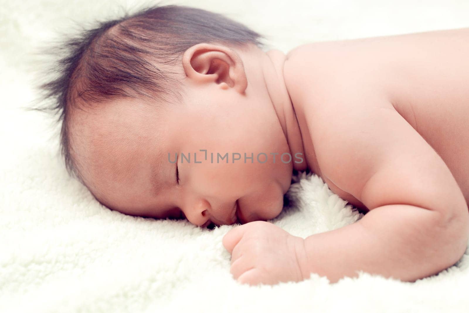 Peaceful baby lying on a bed while sleeping in a bright room over white sheet
