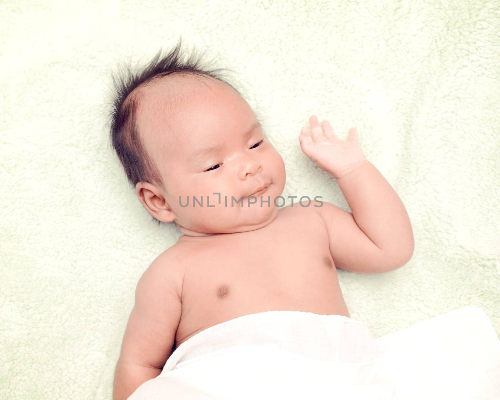 Peaceful baby lying on a bed while sleeping in a bright room over white sheet