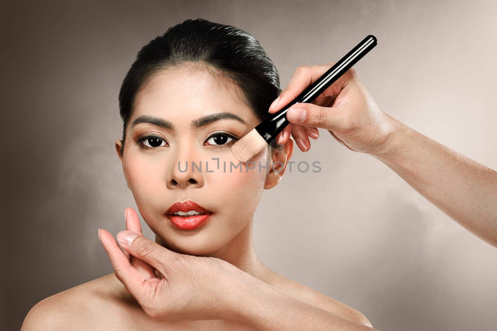 Beautiful asian woman doing makeup over blur background