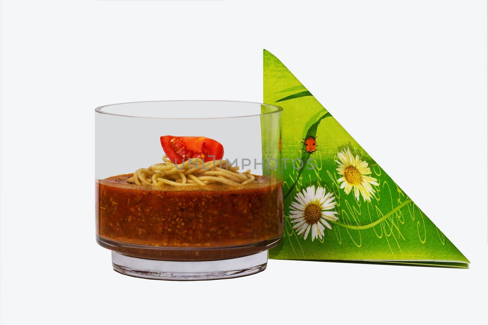 Sauce Bolognese in a glass with a mountain of spaghetti and tomato.