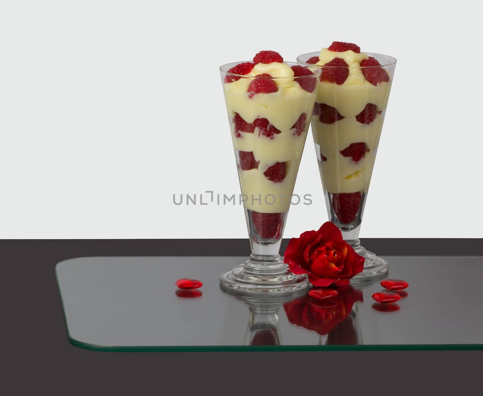 Two glasses with raspberry-vanilla cream and roses décor.