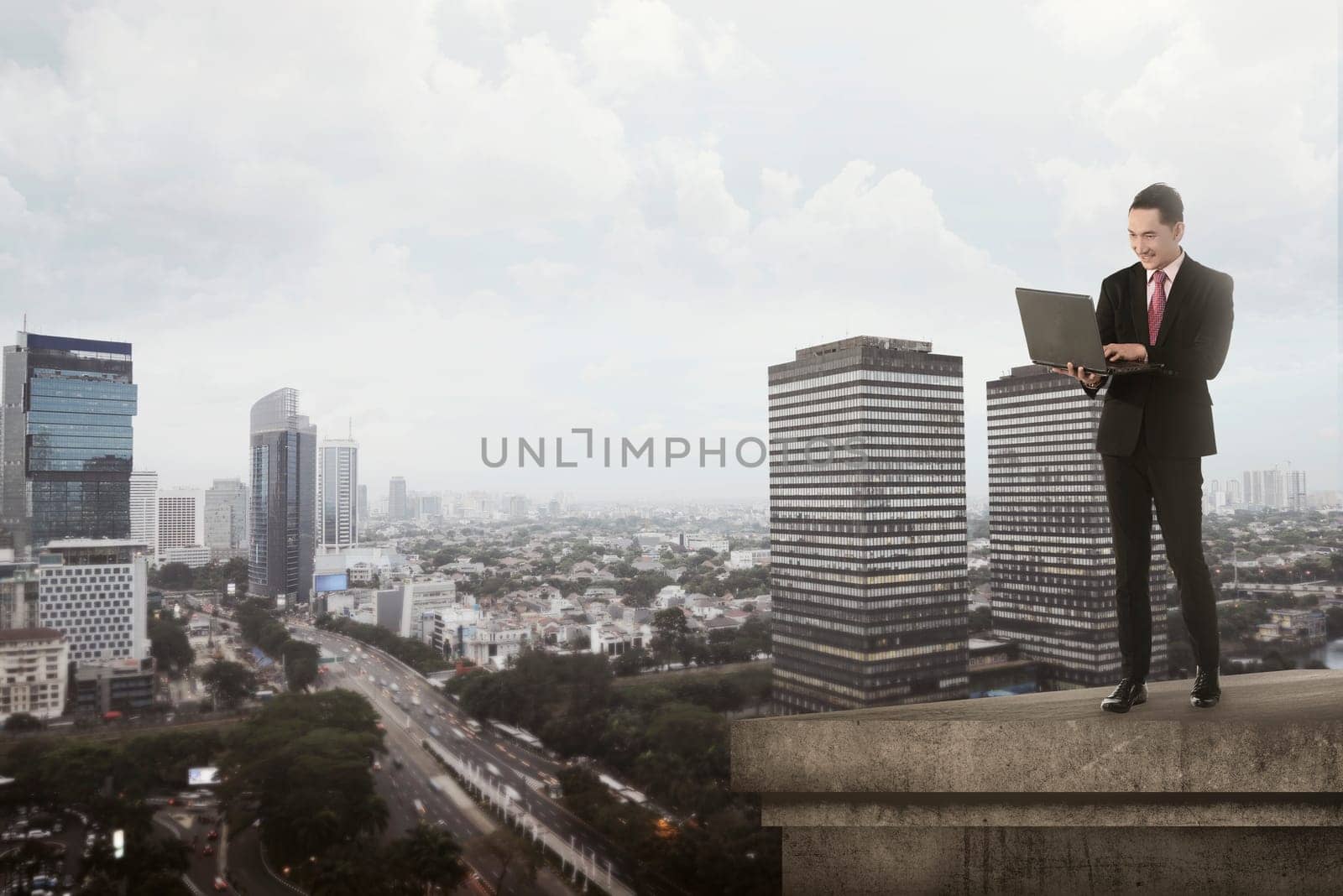 Asian business man typing using laptop on the top of the building