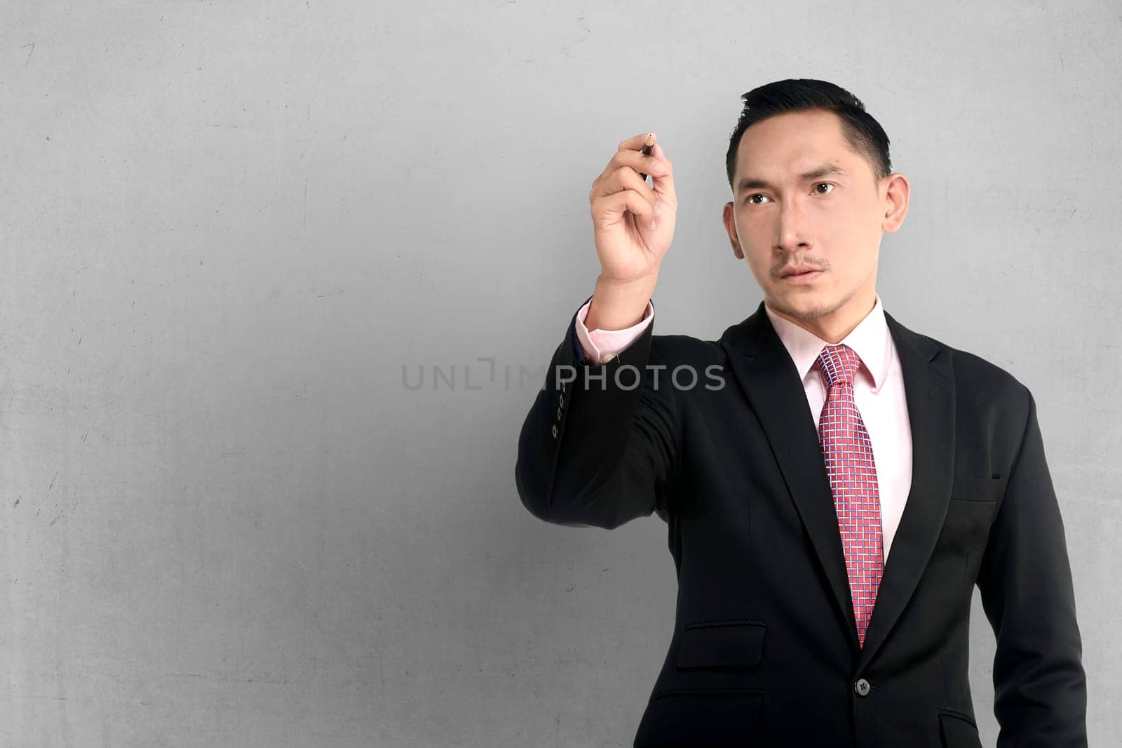Asian business man write something over grunge wall