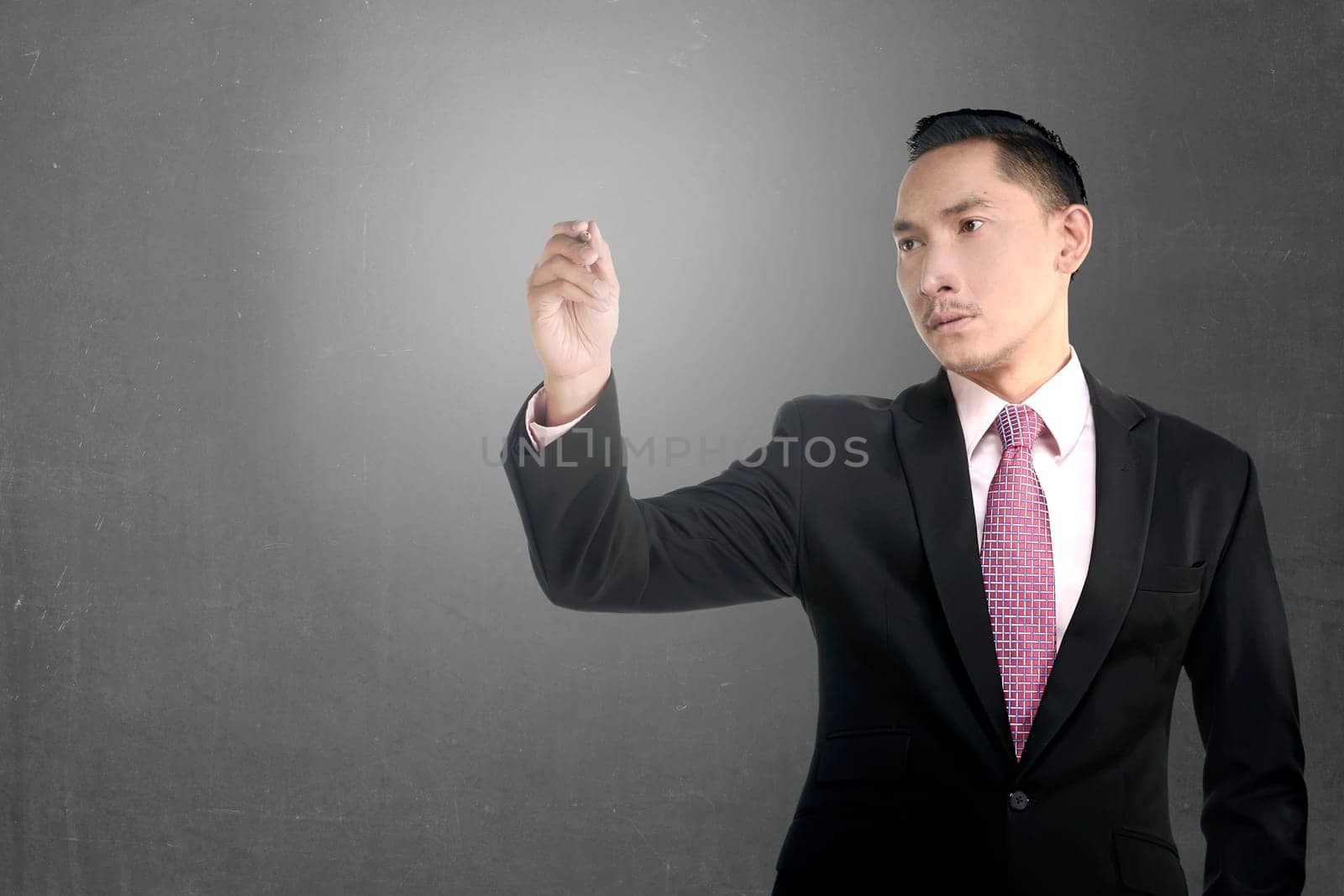 Asian business man write something over grunge wall