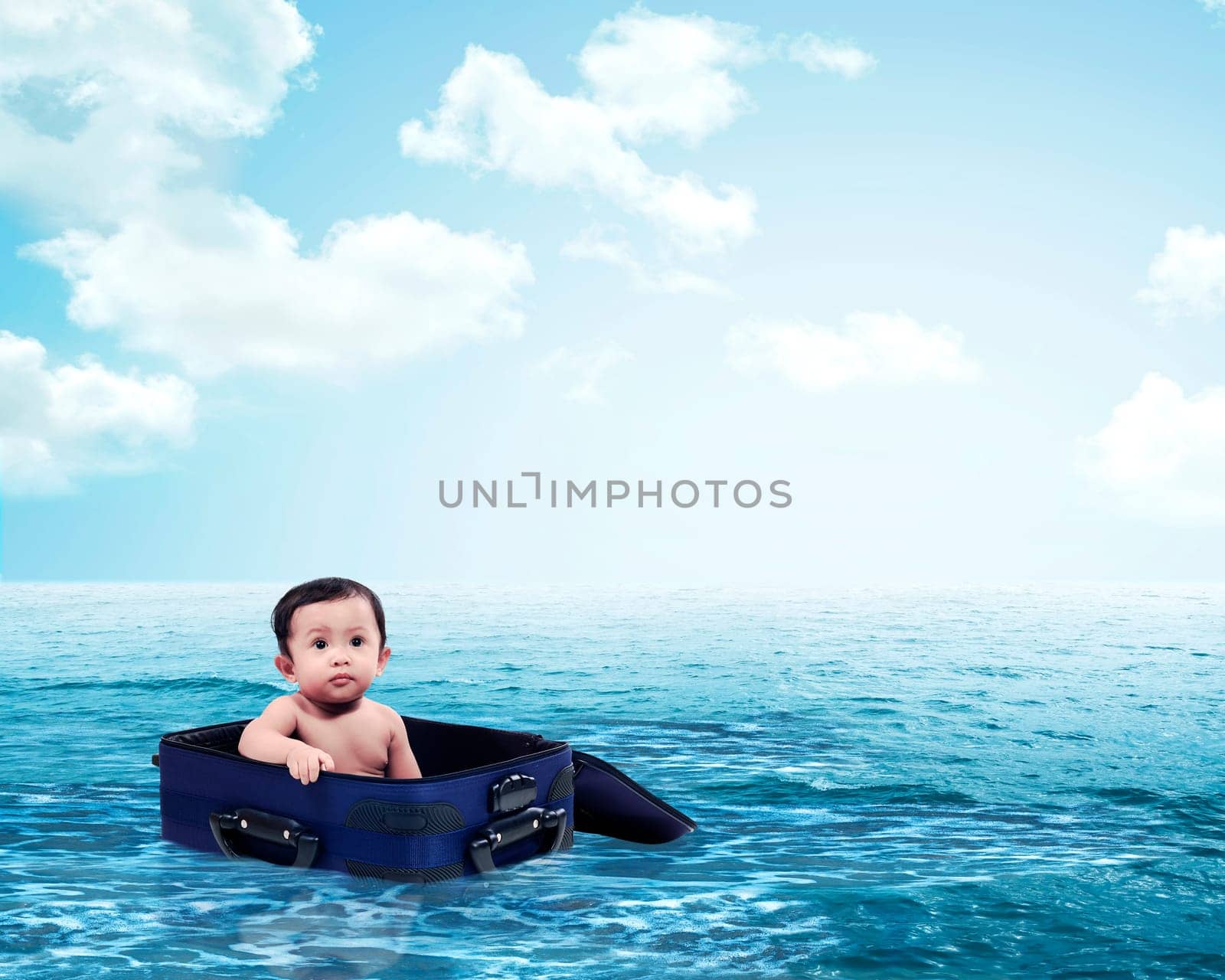 Cute baby in sailing with suitcase on the ocean