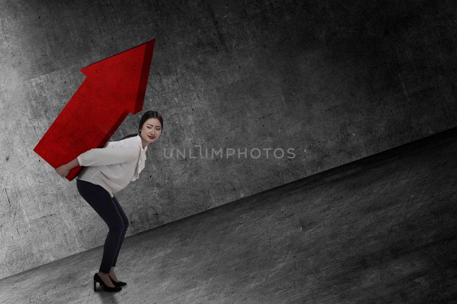 Asian business woman lifting heavy arrow. Business challenge concept